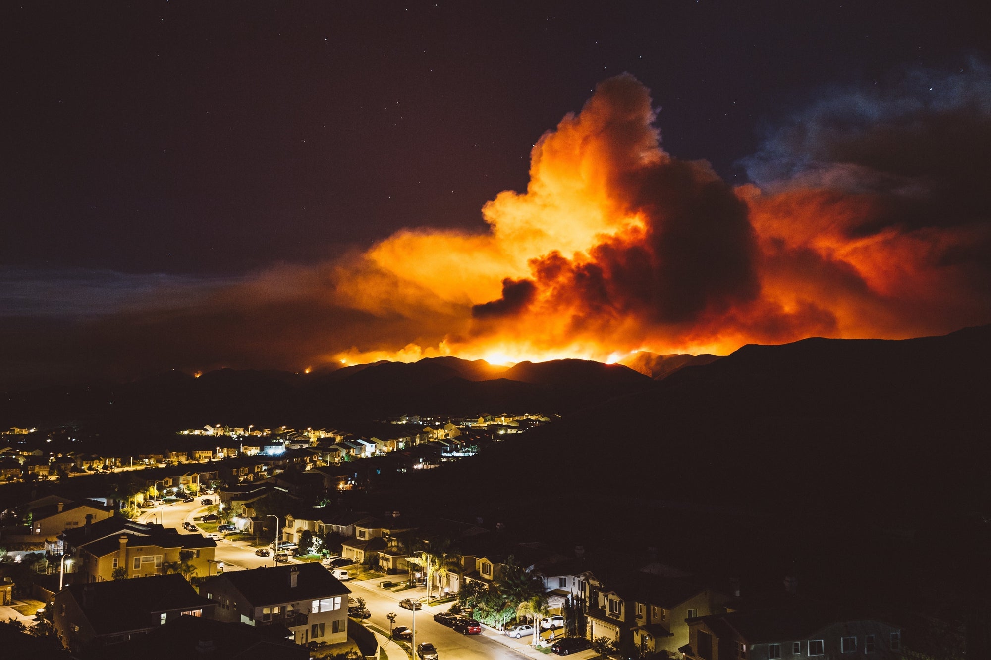 Large wildfire approaching residential homes during high wind conditions