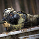 Soldier laying down while aiming through a rifle, while wearing the CM-7M military mask