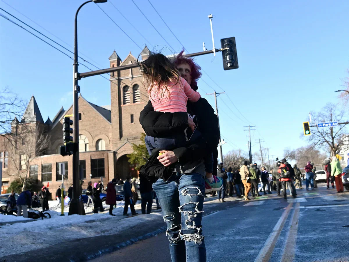 Parent protecting child from protest crowd and tear gas exposure