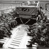 Black-and-white photo of U.S. Army soldiers seated inside a military cargo aircraft with a Humvee secured by chains during troop transport.