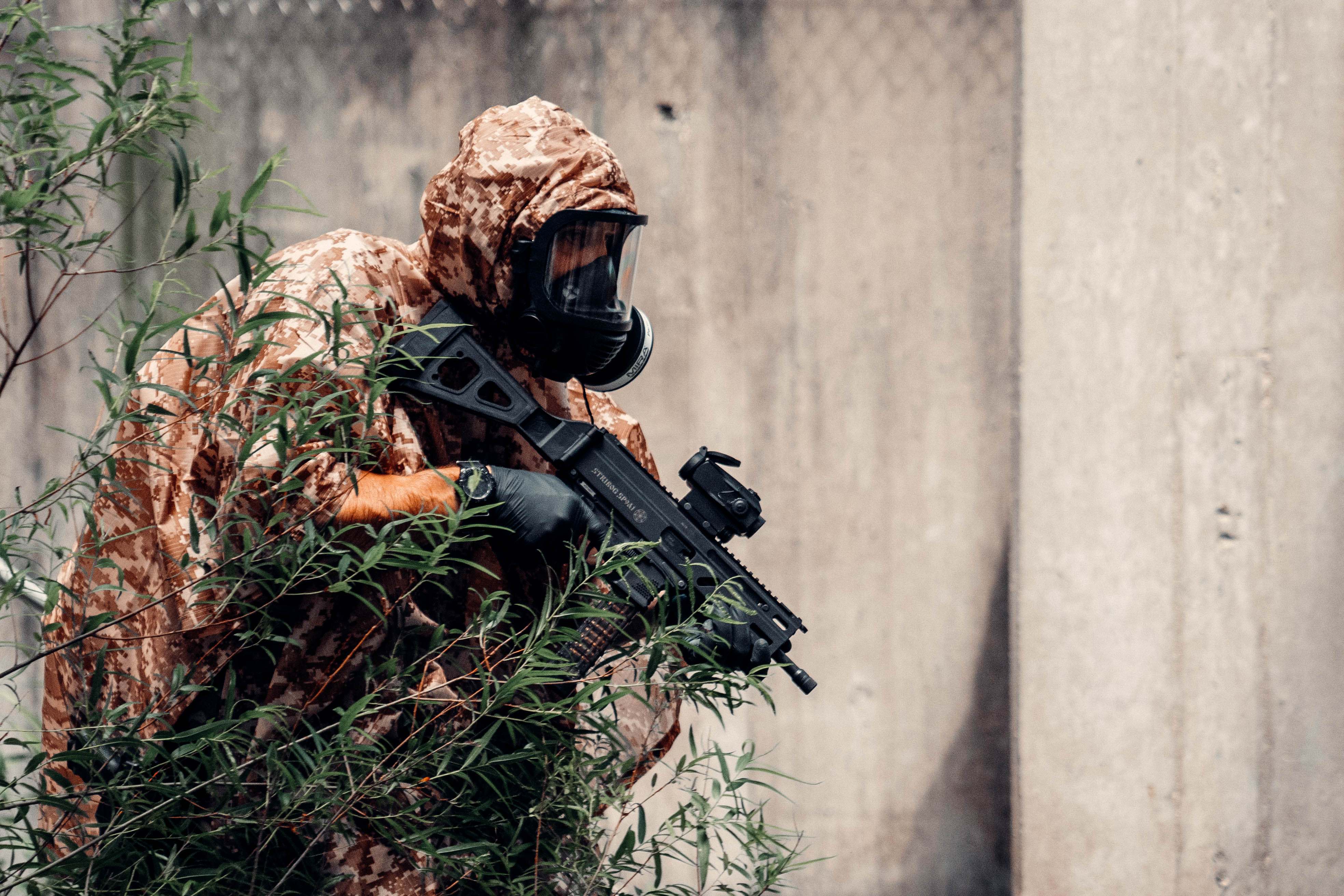 A Sniper In A Camouflage Suit Poncho And Gas Mask With A Sniper