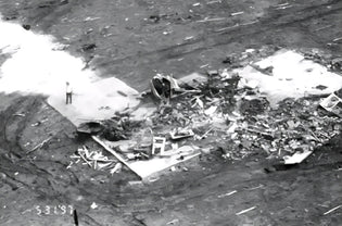 Aerial view of tornado destruction showing debris, collapsed structures, and emergency response foam on the ground after a powerful storm in a rural area.