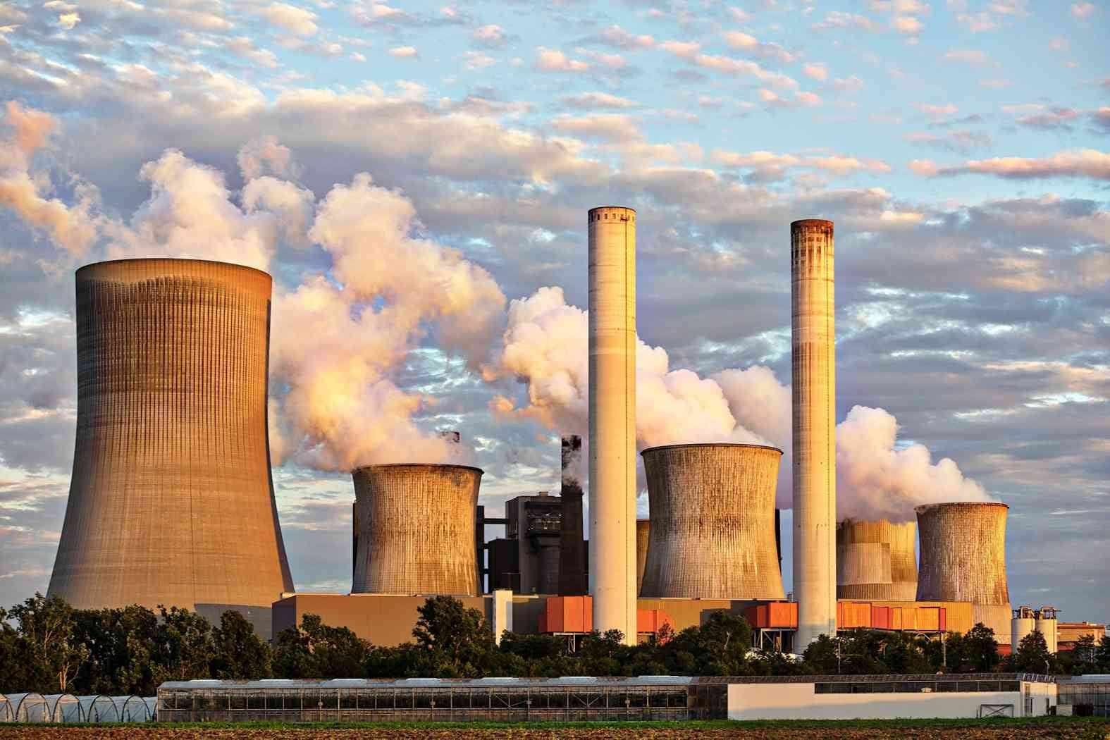 Industrial power plant releasing steam and heat into the atmosphere, contributing to thermal pollution and environmental impact