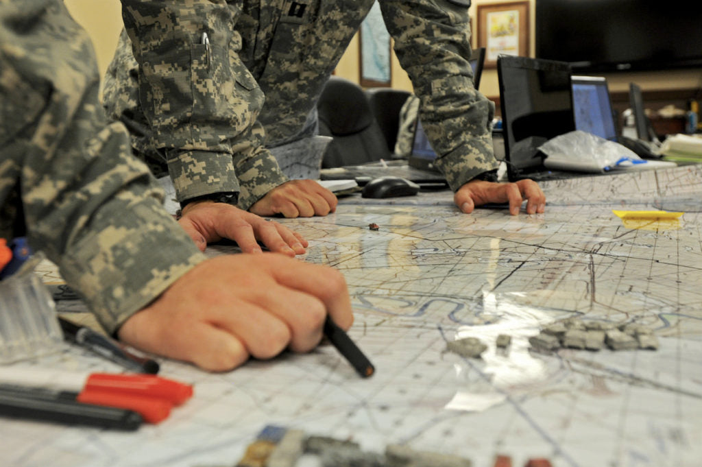 Soldiers hunched over a map