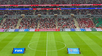 Aerial view of a soccer match kickoff in a vibrant, full stadium.
