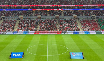 Aerial view of a soccer match kickoff in a vibrant, full stadium.