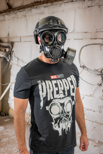 Person wearing a gas mask and 'The Prepper' t-shirt in an industrial setting