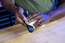 Person using a garlic press on a wooden surface