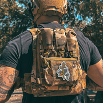 Back view of Male wearing a tactical plate carrier with Slav Squat morale patch velcroed to front chest while holding an AR-style rifle. Also wearing TAPR with P-CAN