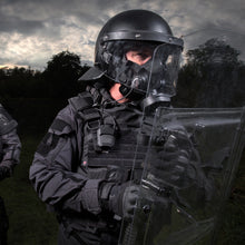 Medium shot, 3/4 view of a riot control police officer wearing a TAPR mask using the MSA gallet adapter kit attached to a riot helmet.