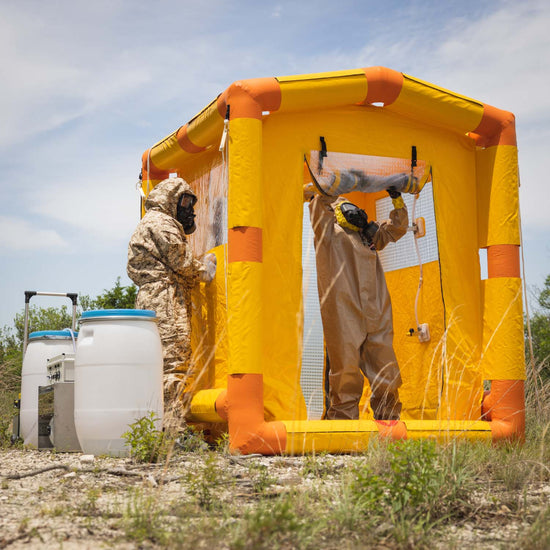 A man in a hazmat suit is exiting through the back end of the decontamination shower.