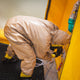 A man wearing a hazmat suit inside of the decontamination shower is tightening the valve switches. The drainage mat can also be seen.
