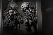 Two SWAT members breaching a door while wearing the Tactical Air-Purifying Respirator mask (TAPR)