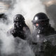 Two SWAT members deploying tear gas while wearing the Tactical Air-Purifying Respirator mask (TAPR)