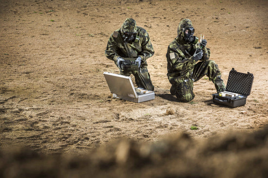 Two soldiers testing ground samples with the CM-7M warfare mask